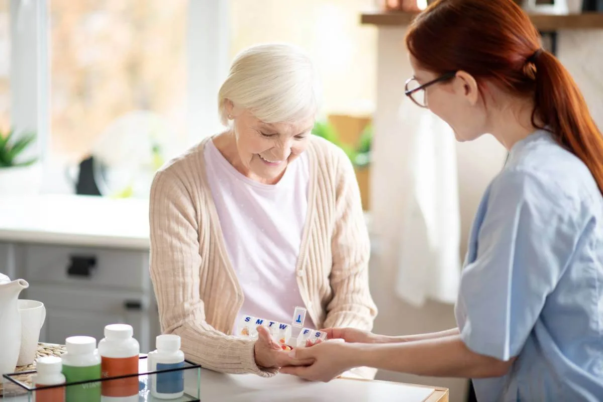 Νοσηλεύτρια βοηθά ηλικιωμένη με άνοια στη διαχείριση φαρμακευτικής αγωγής στο σπίτι